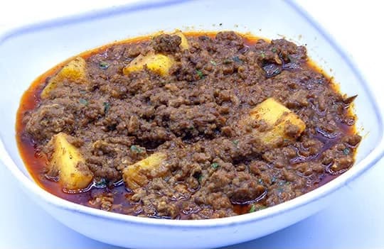 Qeema Masala served in a white bowl with potato and a spiced oil finish